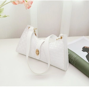 Detail of white baguette bag with textured circular pattern and gold twist lock