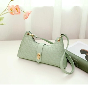Detail of mint green handbag featuring geometric embossed texture and gold twist-lock