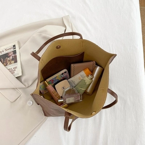 Grand sac cabas en cuir marron montrant un intérieur spacieux avec des objets du quotidien