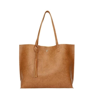 Grand sac cabas marron en similicuir avec texture vintage et pompon sur fond blanc