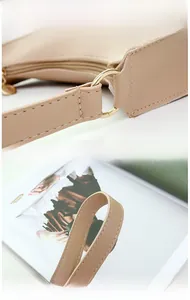Detail view of gold circular hardware and premium stitching on beige handbag handles