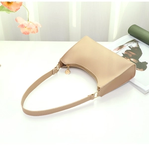 Chic beige faux leather baguette shoulder bag with gold zipper detail and fashion magazine