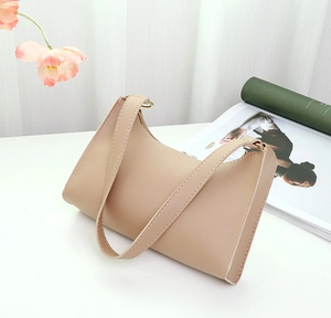 Detail of minimalist beige faux leather hobo bag with sleek strap and metallic buckle