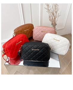 Close-up of five quilted leather crossbody bags in various colors on a mirror base