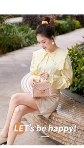 Close-up of pink floral pattern handbag with gold clasp on model in outdoor setting