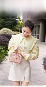 Outdoor shot of a pink monogram patterned handbag styled with a vintage lace collar shirt