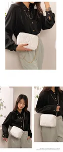 Detailed view of white quilted crossbody bag with gold chain strap worn by a model