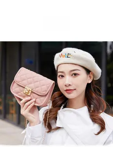 Close-up of pink quilted crossbody bag with metal twist lock and chain strap