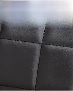 Macro detail of black quilted bovine leather showing fine texture and stitching
