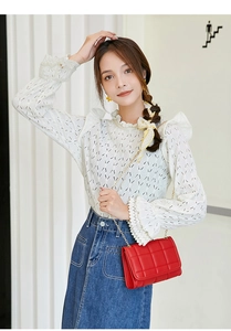 Close-up of red quilted flap bag with gold chain strap on model in lace shirt