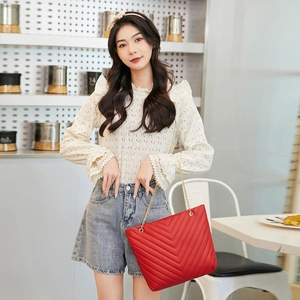 Detail of red V-quilted faux leather shoulder bag with elegant gold chain strap