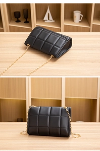 Macro shot of black quilted faux leather flap bag and luxury light gold chain strap