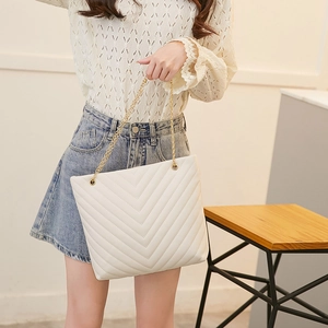Detail of ivory white tote bag with V-shaped quilting and golden chain strap