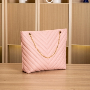 Close-up of pink tote bag with V-shaped quilted embroidery and gold chain strap