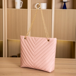 Detail of light pink quilted tote bag with V-shaped stitching and gold chain handles