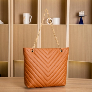 Detail of brown quilted tote bag with V-shaped stitching and golden chain handles