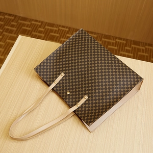 Detailed close-up of brown crocodile pattern tote bag with gold rivets on a wooden table