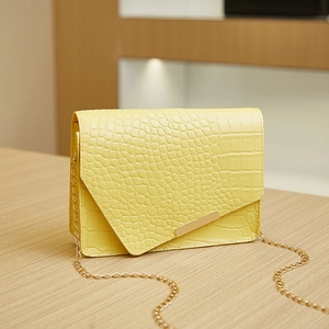Detail of light yellow crocodile pattern small square bag with gold metal edge trim