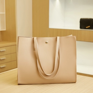Detail of a large beige tote bag showing the fine leather texture and gold magnetic clasp
