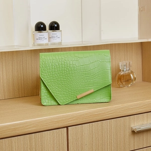 Detail of green crocodile texture small square bag with elegant gold metal trim