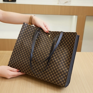 Close-up of brown tote bag with geometric print, slim black handles and gold snap closure