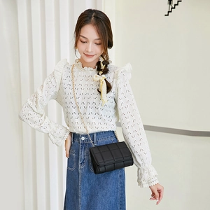 Chic black quilted square crossbody bag with gold chain strap on model in casual outfit