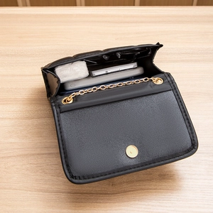 Quilted black crossbody bag with gold chain strap and open flap showing interior storage