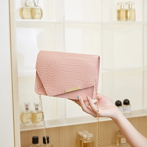 Pink faux leather crossbody bag with crocodile embossing and gold chain strap