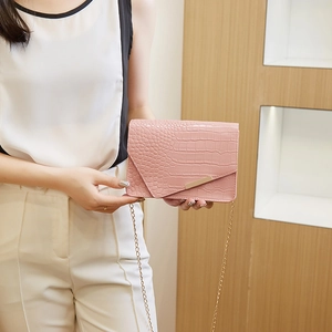 Detailed close-up of pink faux crocodile leather bag with gold chain and metal accent