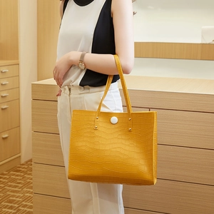 Detail of bright yellow crocodile embossed tote bag worn with a stylish office outfit