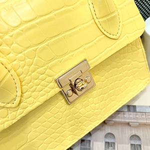 Detail of yellow crocodile embossed leather handbag with golden square metal buckle