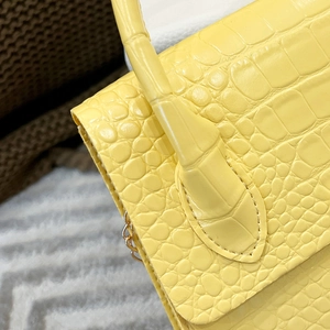 Detailed close-up of yellow crocodile pattern leather handbag with precise stitching