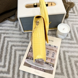 Detail of bright yellow faux crocodile leather shoulder bag with golden chain strap