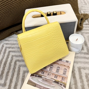 Detail of yellow crocodile embossed PU leather handbag with gold chain and handle