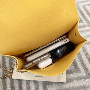 Internal capacity of yellow felt chain bag showing phone, power bank and earbuds