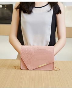 Close-up of pink croc-effect small square bag with gold chain strap and metal trim