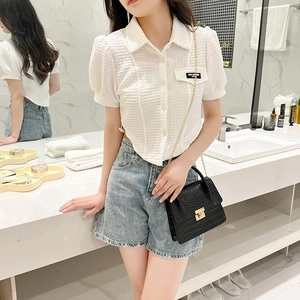 Close-up of white waffle texture shirt with irregular hem and chain crossbody bag details