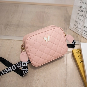 Detail of light pink quilted camera bag with butterfly clasp and woven crossbody strap