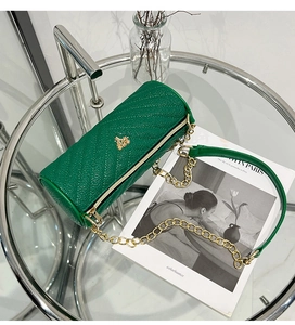 Vue détaillée du sac polochon vert avec texture litchi et logo doré élégant