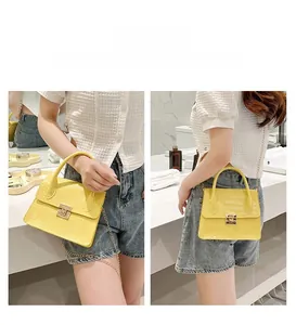 Detail of yellow crocodile texture crossbody bag with gold square lock and chain strap
