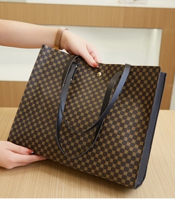 Detail of a brown tote bag with vintage circular patterns and black leather handles