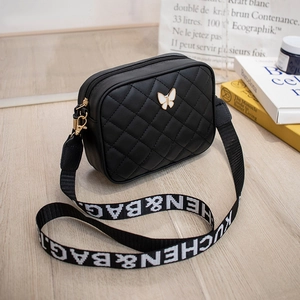 Detail of black quilted camera bag with white butterfly buckle and logo strap