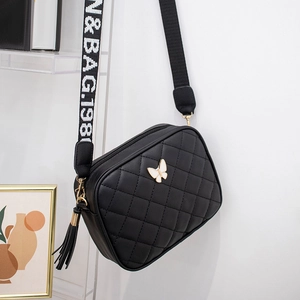 Detail of black quilted camera bag with golden butterfly logo and woven logo strap