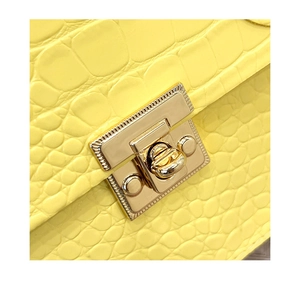 Close-up of bright yellow crocodile embossed leather with vintage gold metal lock