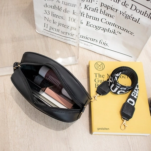 Detail of black diamond lattice camera bag showing open zipper with daily essentials