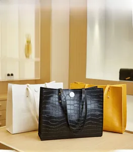 Detailed view of large tote bags with crocodile texture and circular magnetic closures