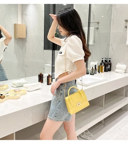 Detail of yellow crocodile embossed small handbag with gold buckle and chain strap