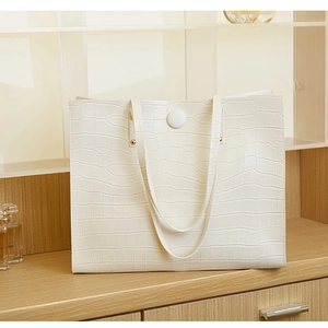 Detail of white crocodile pattern tote bag featuring silver studs and textured PU leather