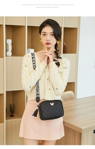 Detail of black quilted camera bag with gold butterfly clasp and tassel charm