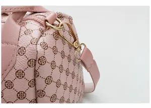Close-up detail of high-quality gold metal hardware on pink heart printed barrel handbag